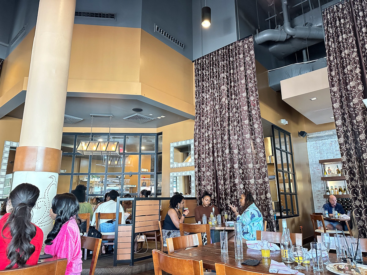 inside restaurant with tall ceilings and brown designed curtains